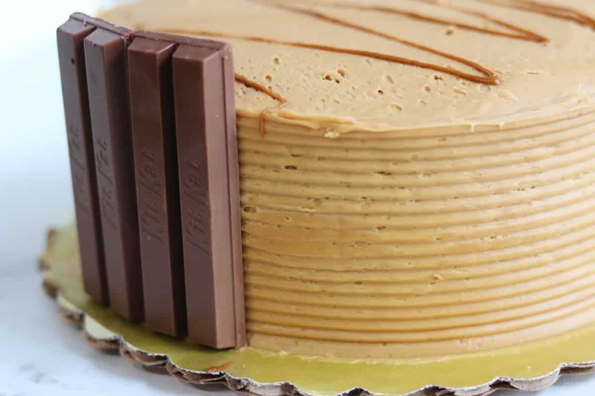 Close up of a cake with KitKat bars around the sides and caramel drizzle on top.