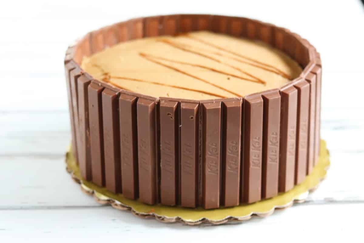 Cake wrapped in KitKat bars on a gold cake board.