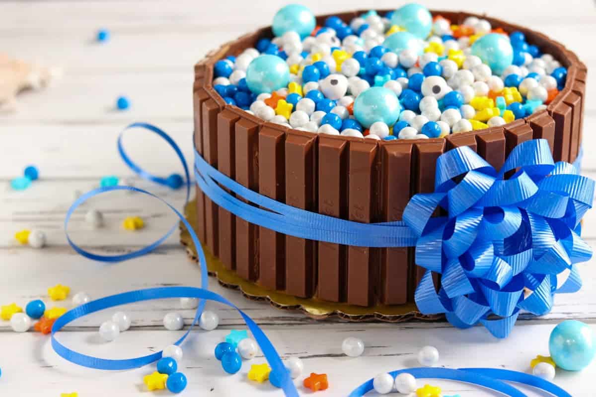 KitKat cake filled with blue, white, and yellow candy sprinkles and tied with a blue ribbon bow.