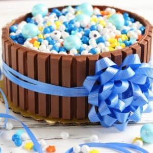 KitKat cake decorated with blue candy balls and a large blue ribbon bow.