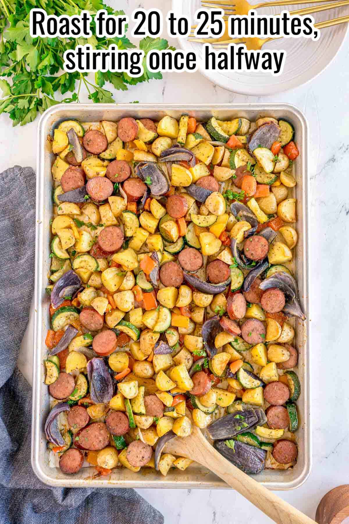 Step four of making sheet pan sausage and veggies: the fully roasted sausage and vegetables on the sheet pan, golden and caramelized, with a wooden spoon resting in the pan. Text reads: Roast for 20 to 25 minutes, stirring once halfway.