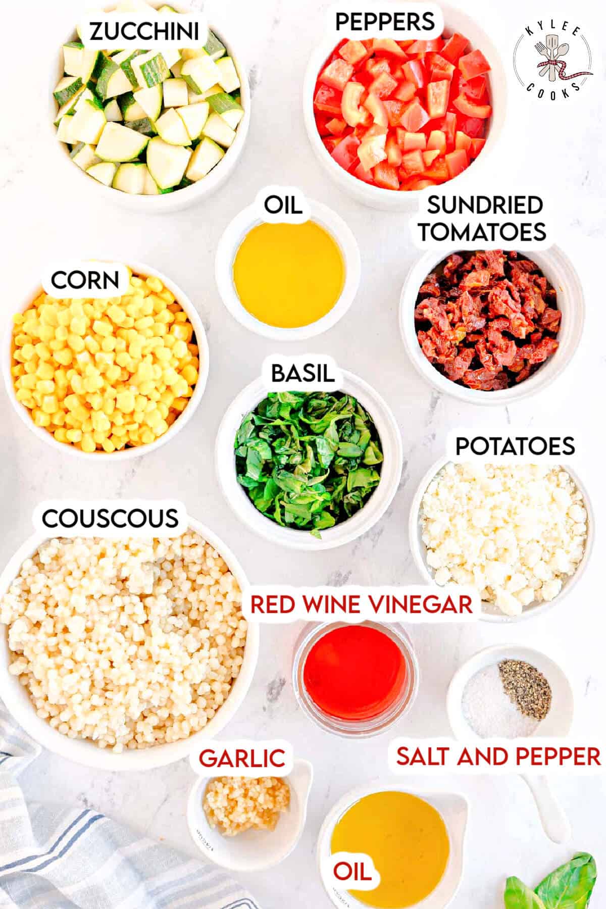 Bowls of chopped zucchini, peppers, corn, sundried tomatoes, potatoes, couscous, basil, red wine vinegar, garlic, oil, and salt and pepper arranged on a white surface.