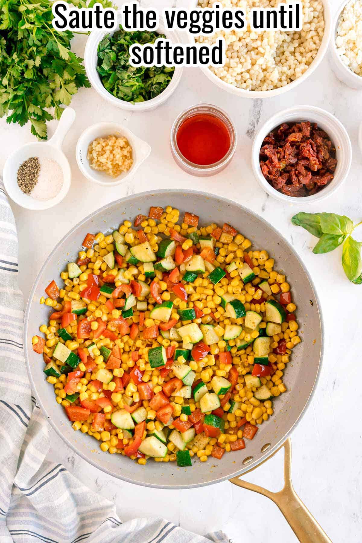 A skillet with sautéed corn, zucchini, and red bell pepper sits on a countertop surrounded by bowls of chopped ingredients—perfect for creating a vibrant Summer Couscous Salad bursting with fresh flavors and color.