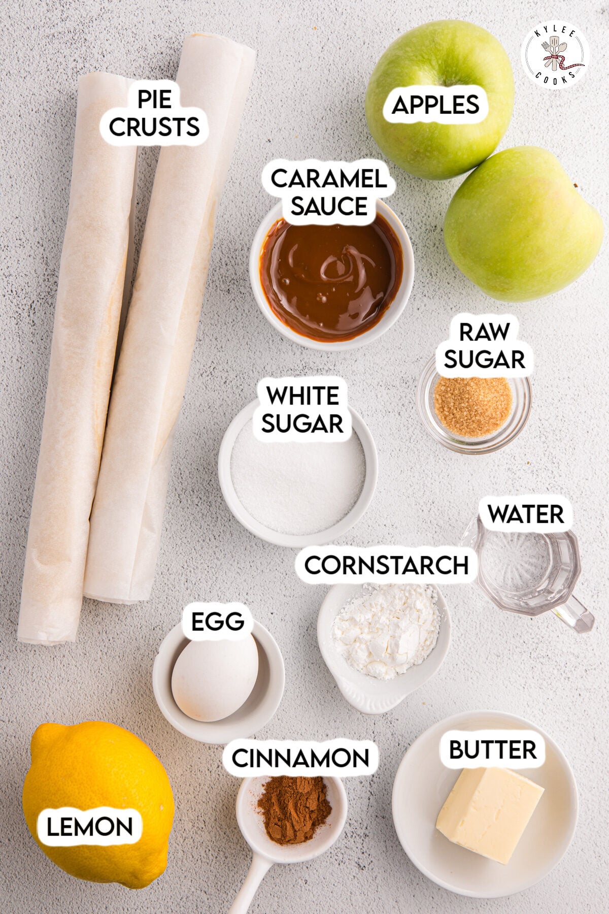 Two rolled pie crusts, a bowl of caramel sauce, and two green apples are labeled on a light surface—perfect for making apple pie cookies.