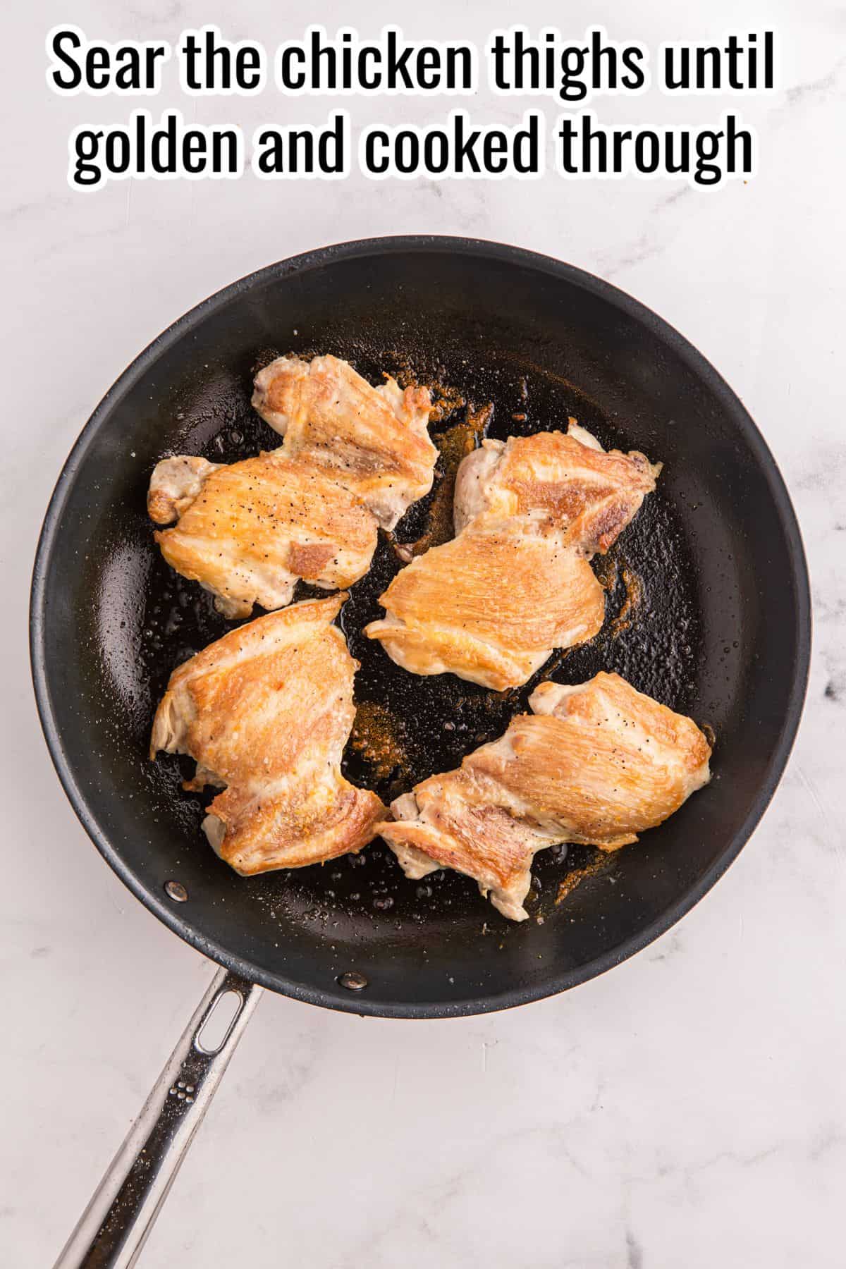Five chicken thighs are searing in a black skillet on a white marble surface, with a caption instructing to sear the chicken until golden and cooked through.