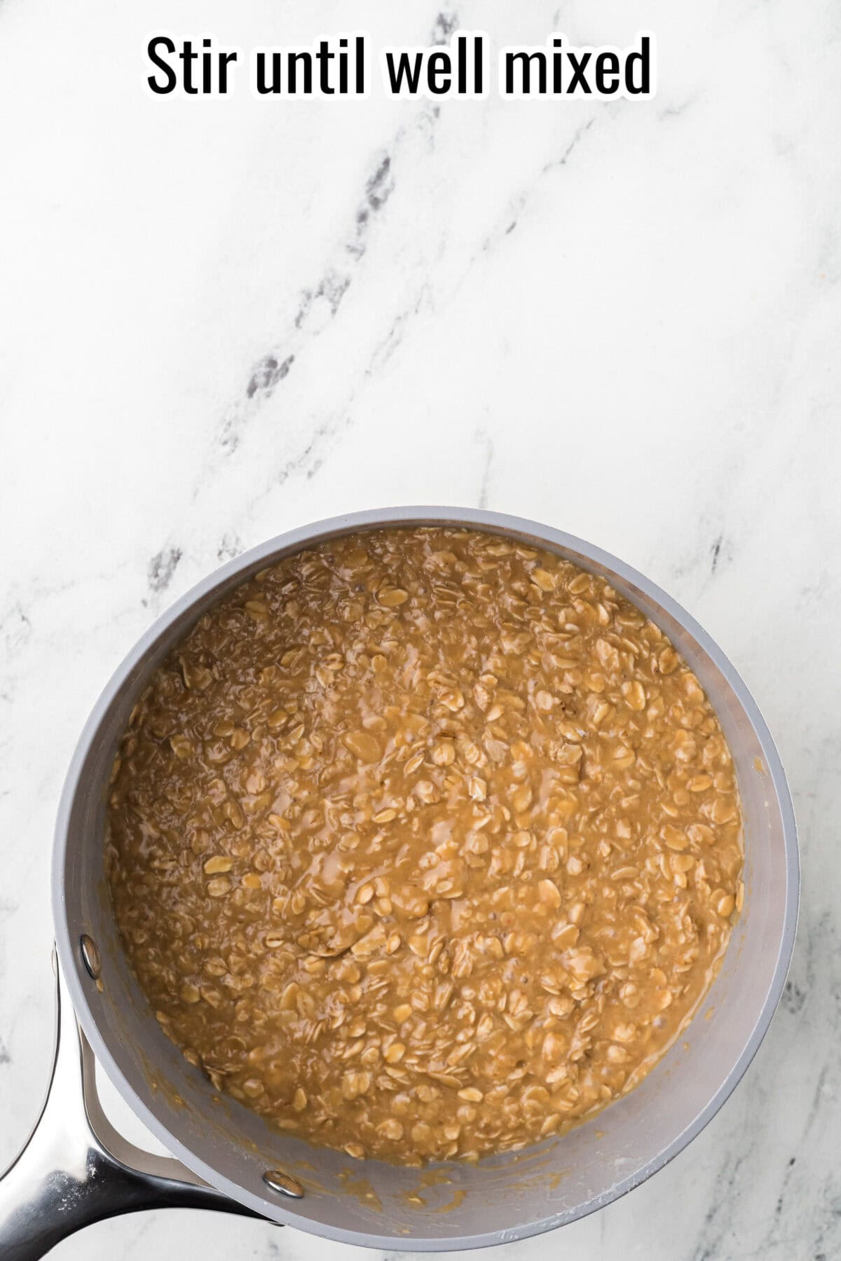 A pot of brown oatmeal mixture being stirred, with the text "Stir until well mixed" at the top against a white marble background.