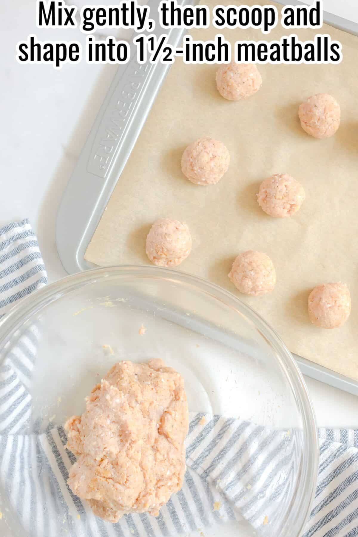 A glass bowl with raw meat mixture, a baking sheet with eight raw meatballs on parchment, and a striped towel on a white surface.