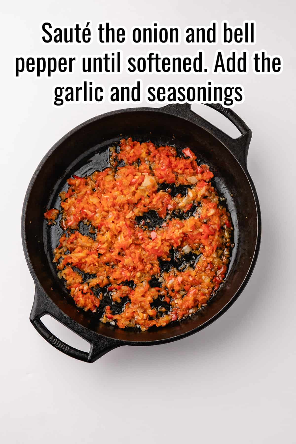 Cast iron skillet containing sautéed chopped onions, bell peppers, and garlic, with the text: “Sauté the onion and bell pepper until softened. Add the garlic and seasonings.”