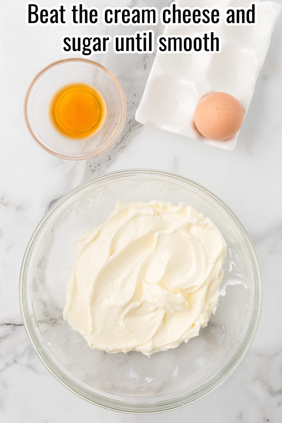 A bowl of cream cheese with a small bowl of vanilla extract and an egg, with the text “Beat the cream cheese and sugar until smooth.”