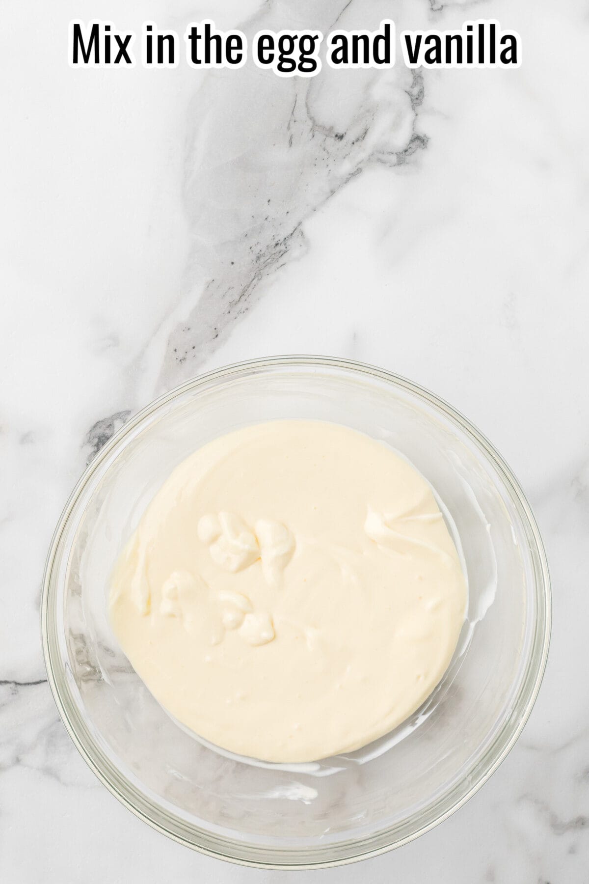 Batter in a glass mixing bowl, with text reading “Mix in the egg and vanilla.”