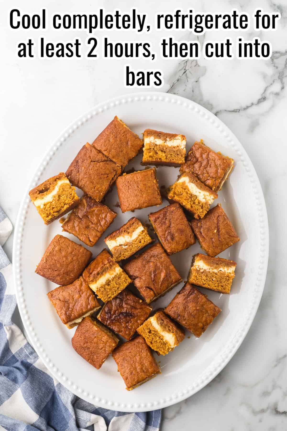 Pumpkin cheesecake bars cut into squares on a white platter. Text overlay reads: “Cool completely, refrigerate for at least 2 hours, then cut into bars.”