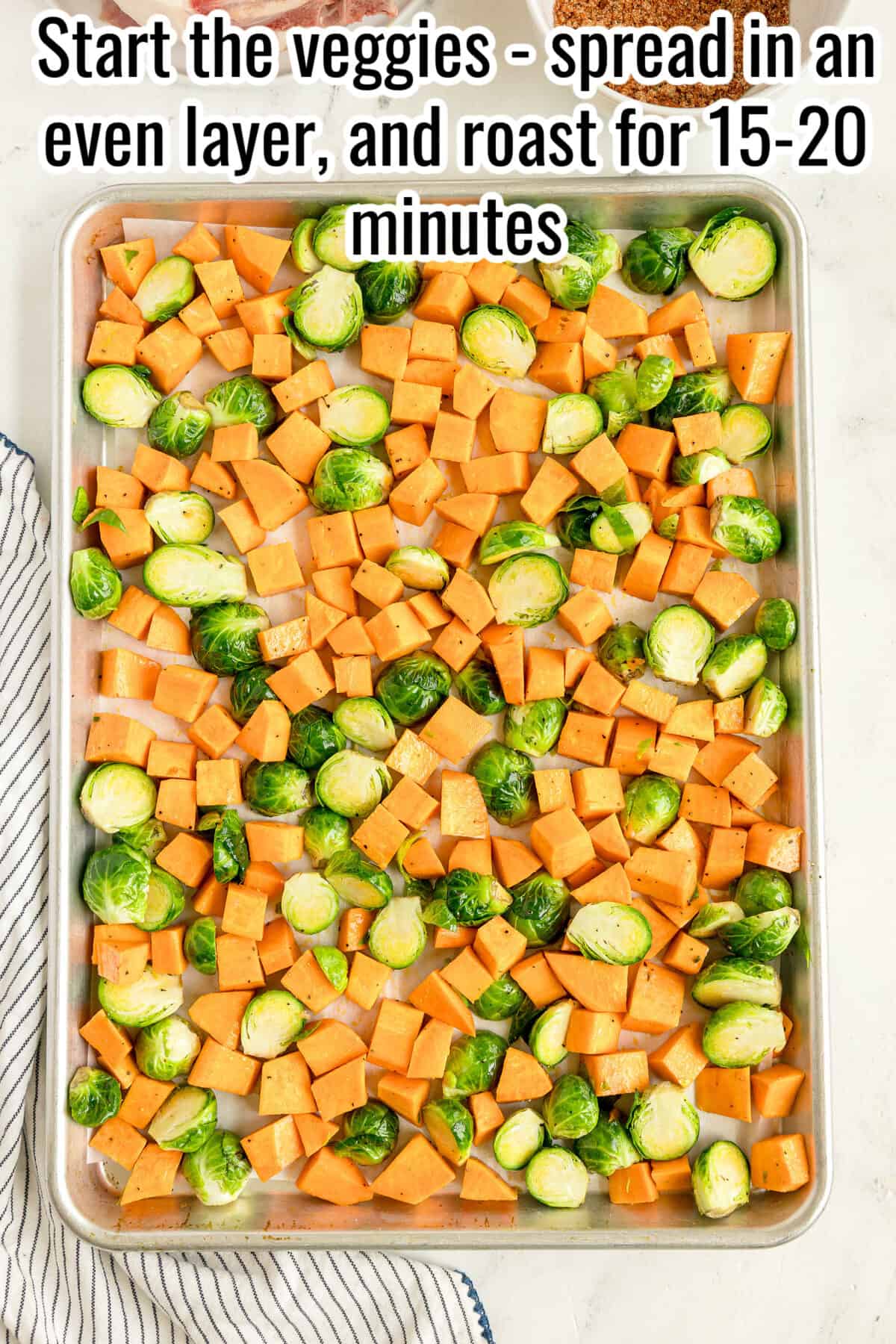 Sheet pan with chopped sweet potatoes and Brussels sprouts arranged in an even layer, ready to be roasted. Text instructs to roast for 15-20 minutes.