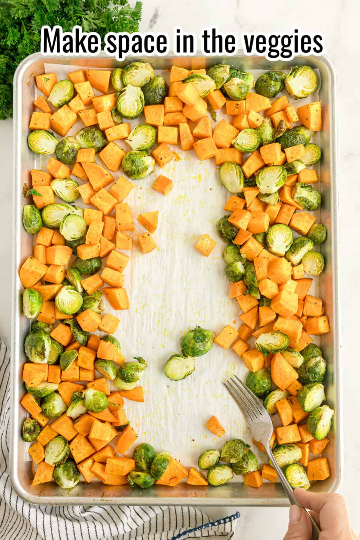 A baking sheet with diced sweet potatoes and halved Brussels sprouts arranged around an empty space in the center, fork in hand, with text: “Make space in the veggies.”.